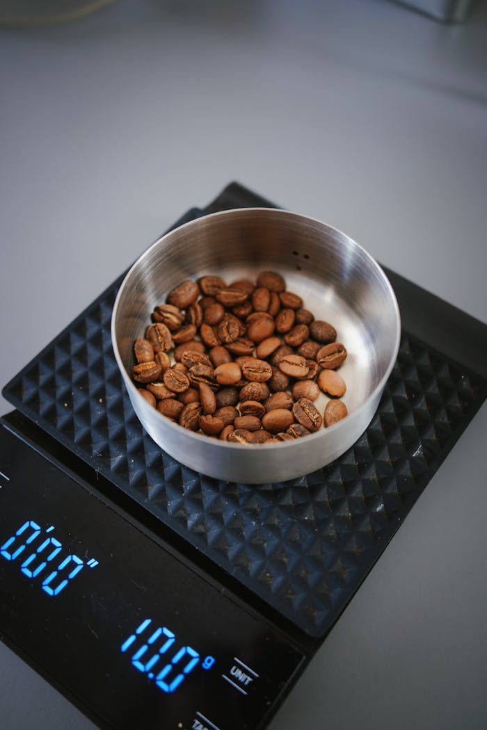 Coffee beans measured on a digital scale in a metal bowl, highlighting precision and quality.